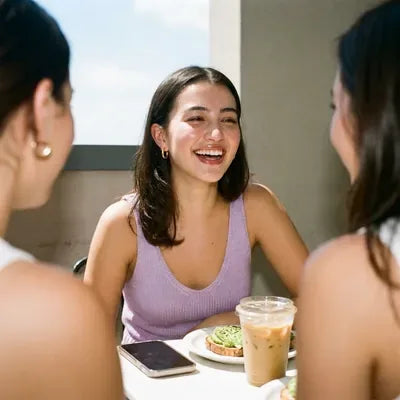 Woman in a lilac knit top laughing with friends over brunch